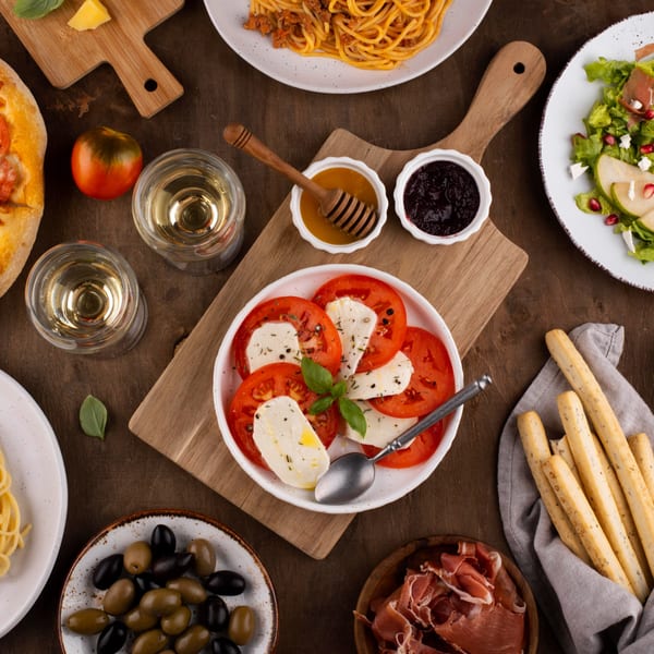 An overhead view of a wooden table laden with various Italian dishes and wine glasses.