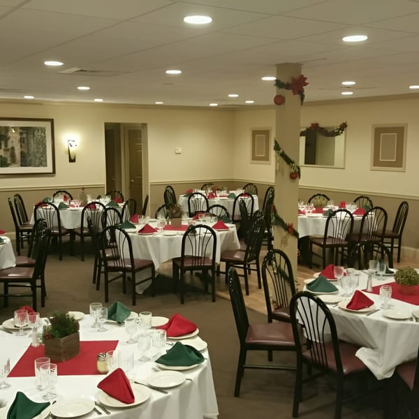 Lena's Restaurant banquet hall with tables set with white tablecloths, red runners, and red and green napkins.