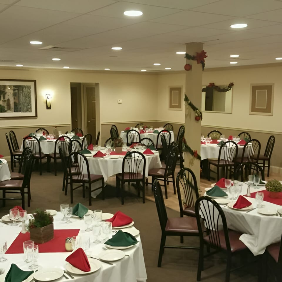Lena's Restaurant banquet hall with tables set with white tablecloths, red runners, and red and green napkins.