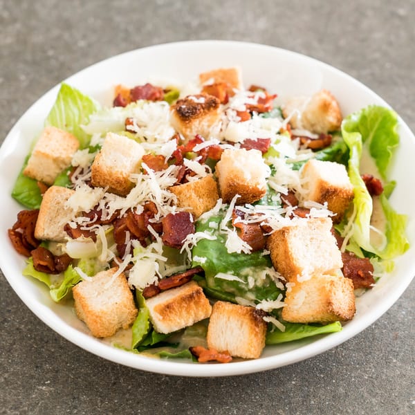 Caesar salad with crisp romaine lettuce, crunchy croutons, crispy bacon, and shredded Parmesan cheese.