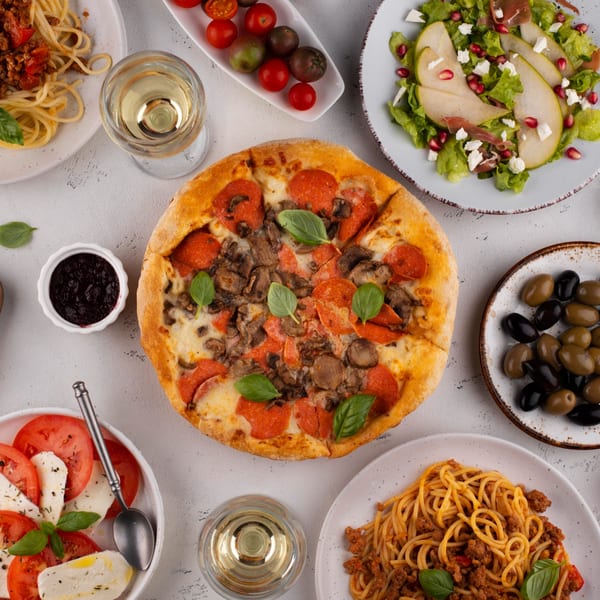 Overhead view of a Lena's Italian feast with pizza, pasta, salads, and wine.